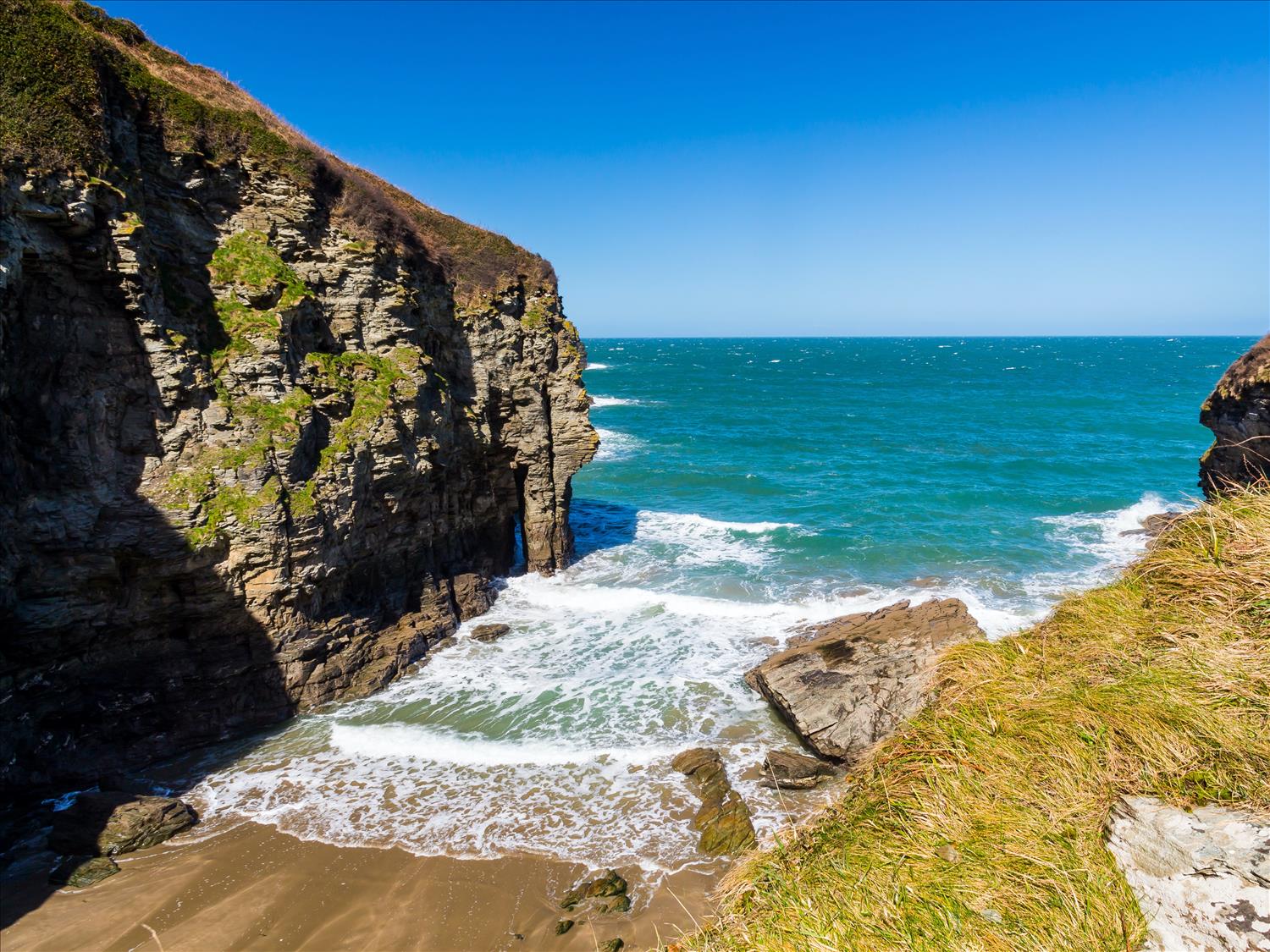 Rolling waves rush into this narrow cove at Bossiney Haven, with tall and steep cliffs rising up either side of this sandy enclave on the SW Coast Path. We walked there from Polrunny Farm