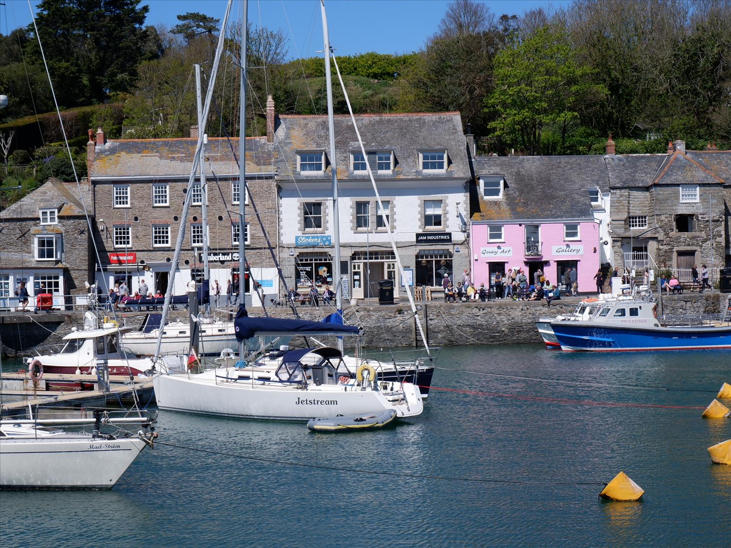 Boats in Padstow Harbour, with tourists exploring the shops and restaurants on the harbour front