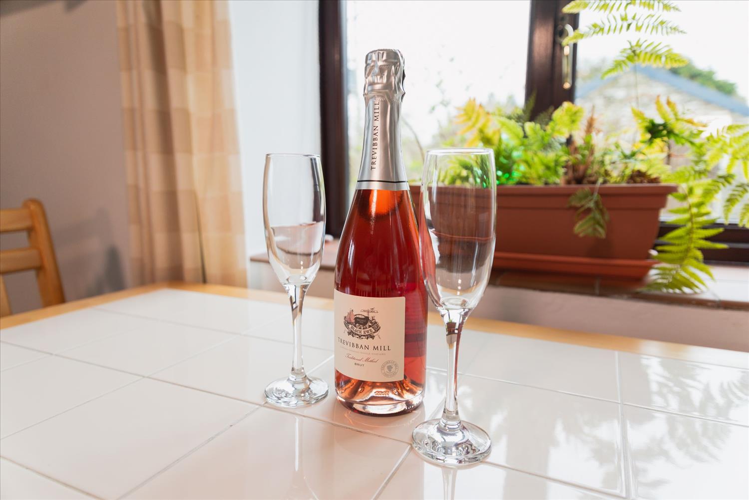 A bottle of pink Cornish fizz and two tall glasses on the table in Seaberry Cottage, Polrunny Farm. I soooo need to open this now.