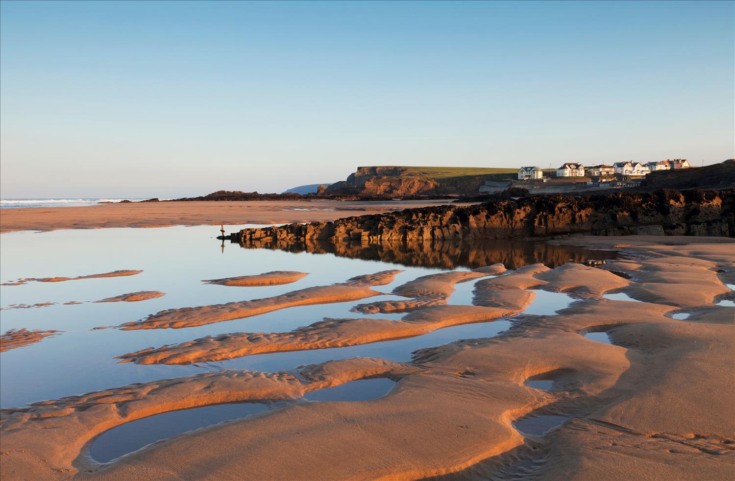 The sand and pools of water at family-favourite Summerleaze Beach near Bude, North Cornwall, lit up by the setting sun on a beautiful clear day