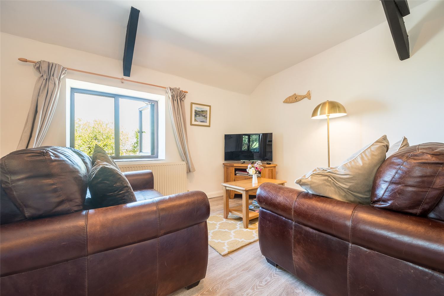 Elderberry Cottage's lounge. As in other properties at Polrunny, a brightly coloured tapestry hangs on the wall above the comfortable brown sofas. 