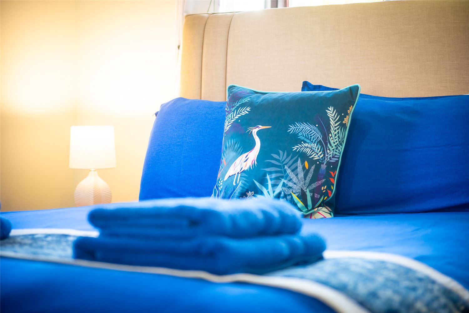 Sloe Cottage's brightly coloured double bedroom, with blue towels placed on top of a multi-coloured bedspread.